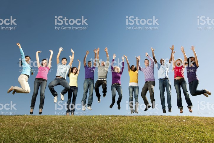 A large group of vibrant young adults outside with a sky background